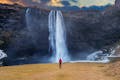 A person standing in front of a huge waterfall.