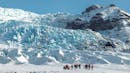 A group of people walking on a glacier plateau.