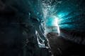 Person looking at the ceiling of an ice cave, the ice cave have layers of ashes inside from previous volcanic eruptions.