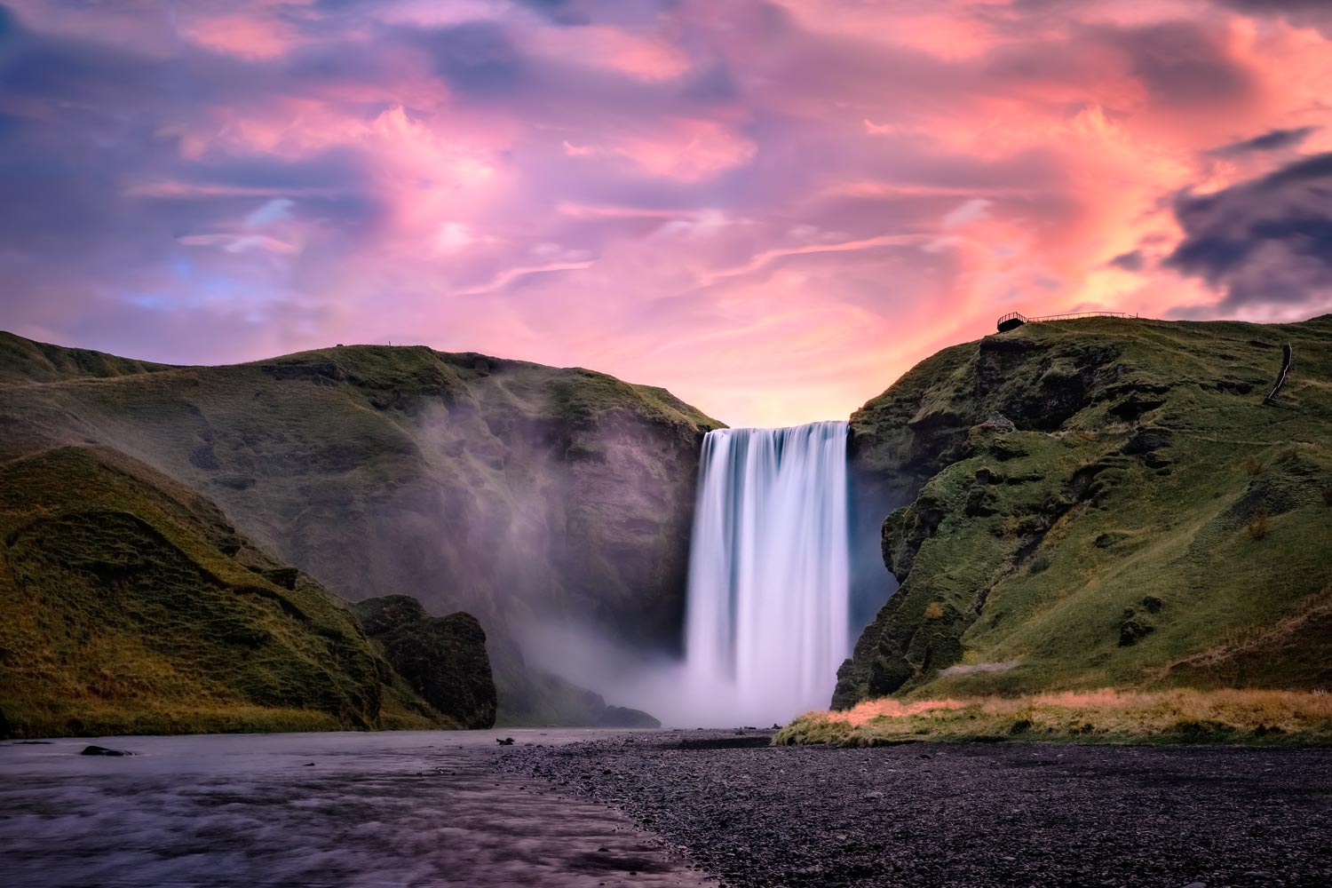 Waterfall surrounded with moss and grass at dusk.