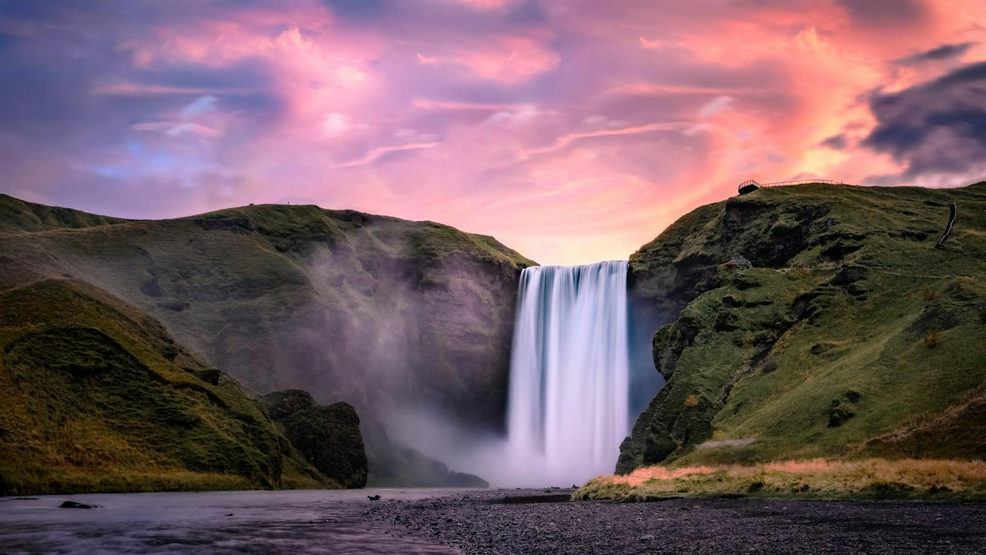 Waterfall surrounded with moss and grass at dusk.