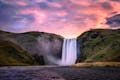 Waterfall surrounded with moss and grass at dusk.