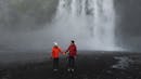 Couple holding their hands with a waterfall behind them.