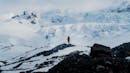 A single person standing and looking at the glacier that is located in distance.