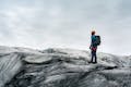 Person wearing a orange helmet standing and looking at the glacier.