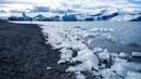 A person standing near the shore of a glacier lagoon.