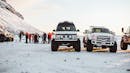 Modified cars parked in the middle of the snow.
