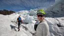 A woman smiling at the camera while her friend still walking toward the to of the glacier.
