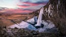 Huge waterfall on a ridge with stalactites of ice and snow on the side walls and floor.