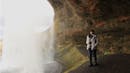 Woman smiling while being behind a waterfall.
