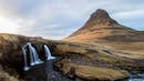 A waterfall on the left with a peaky mountain on the right.